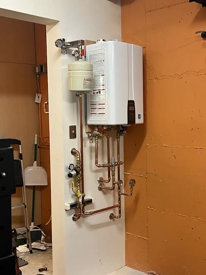Plumbing technician inspecting water heater connections in Rush